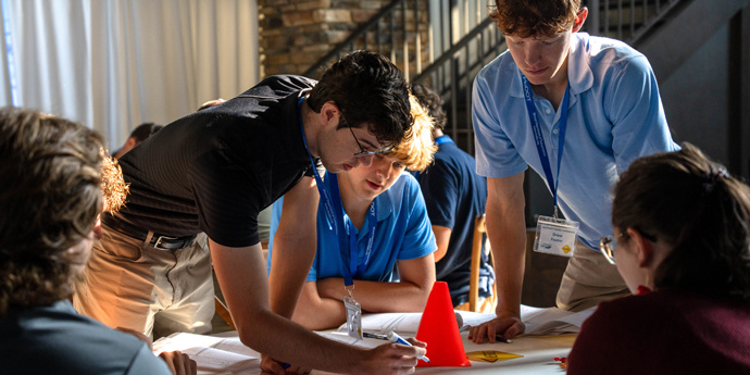 Interns around a table strategize to complete a task